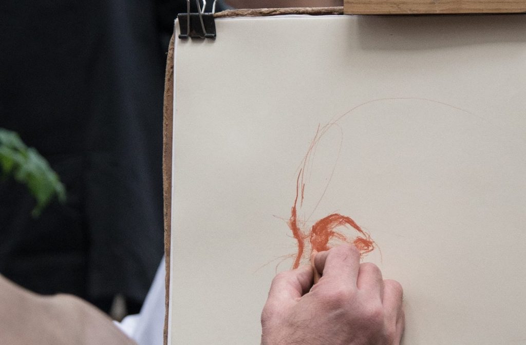 Disegnatore con matita sanguigna su foglio